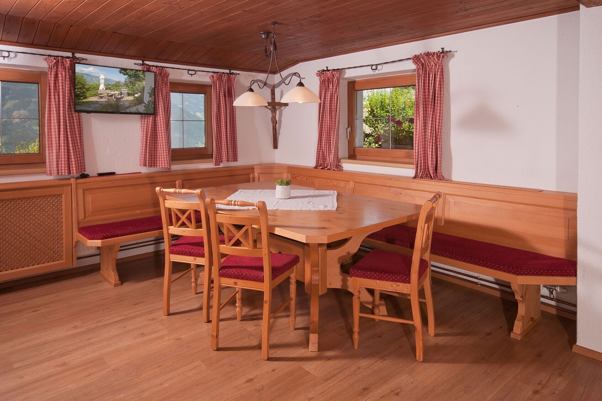 Puisesta materiaalista valmistettu ruokailutila, jossa on penkki, tuoleja ja pöytä.