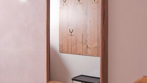 A mirror with a wooden frame and a wall-mounted coat rack with hooks.