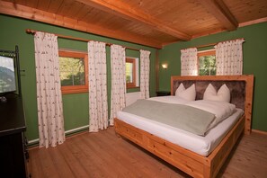 Un lit en bois avec une tête de lit, des murs verts et des rideaux à motifs.