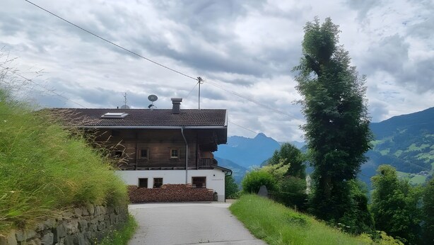A house with a sloped roof, a chimney, and a satellite dish.