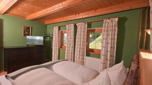 A bedroom with a bed, a dresser, a painting, and a window with curtains.