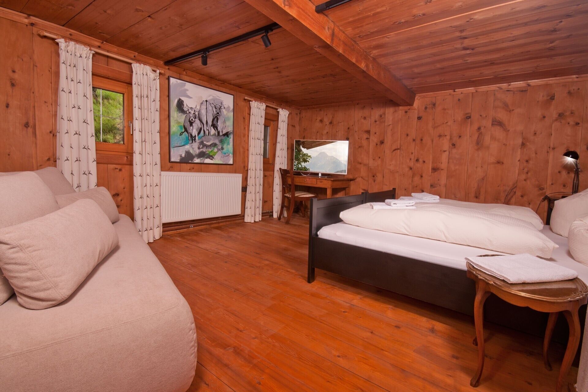 Ein Zimmer in einer Holzhütte mit einem Bett, einem Schreibtisch und einem Fernseher.