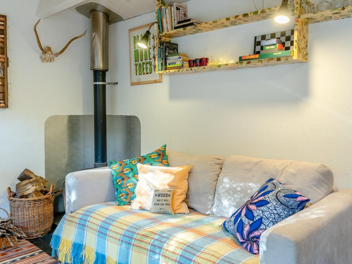 A cozy living room with a sofa, pillows, a blanket, a bookshelf, and a fireplace.