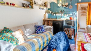 A cozy living room with a sofa, a small kitchen area, and a dining table set for two.