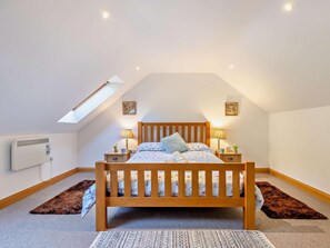 A bedroom with a sloped ceiling, a wooden bed, two bedside lamps, a radiator, and a skylight. - 2 Bed in Arthog (oc-43105) (Arthog)
