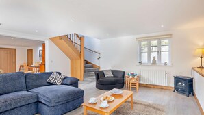 Ein Wohnzimmer mit einer Couch, einem Sessel, einem Couchtisch und einer Treppe.