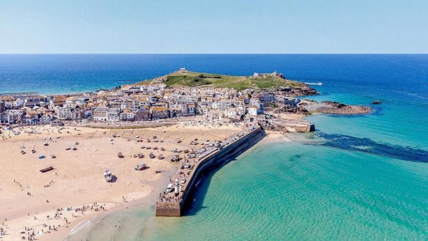 An aerial view of a coastal town with a beach, a fortified structure, and a hilltop with buildings. - 1 Bed in Hayle (oc-43256) (Phillack)