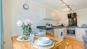 A dining table set with plates, glasses, and a vase of flowers. - 1 Bed in Hayle (oc-43256) (Phillack)
