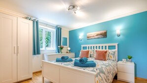 A bedroom with a bed, a nightstand, a window with curtains, a wardrobe, and a ceiling light. - 1 Bed in Hayle (oc-43256) (Phillack)