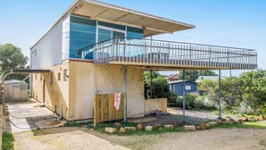 Een gebouw met twee verdiepingen, een balkon, een overdekt terras en een kleine tuin.