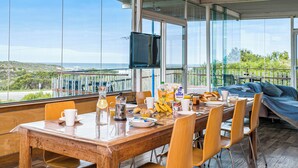Een ontbijttafel met ontbijtartikelen, een televisie en uitzicht op zee.
