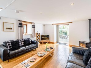 Ein modernes Wohnzimmer mit einer schwarzen Ledersofa, einem Holztisch und einem Fernseher.