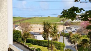 Una calle residencial con casas, cielo despejado y vista a la playa.