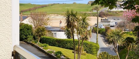 A residential street with houses, a clear sky, and a view of a beach.