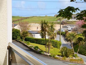 Eine Wohnstraße mit Häusern, wolkenlosem Himmel und Blick auf einen Strand.