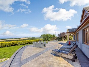 Eine Terrasse mit Gartenmöbeln, einem Briefkasten und Blick auf die Landschaft.