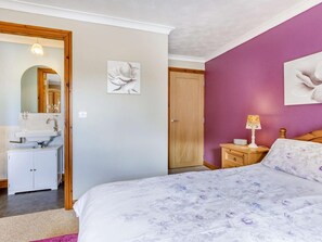 A bedroom with a bed, a nightstand, a lamp, a dresser, a mirror, and a door. - 2 Bed in Bideford (oc-43751) (Higher Clovelly)