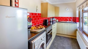 Una cucina con frigorifero, forno e lavatrice, uno schienale in piastrelle rosse e mobili in legno.