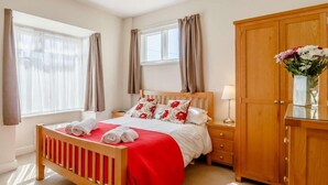 A bedroom with a wooden bed, a nightstand, a wooden wardrobe, and a window with curtains. - 3 Bed in King's Lynn (oc-43259) (Dersingham)