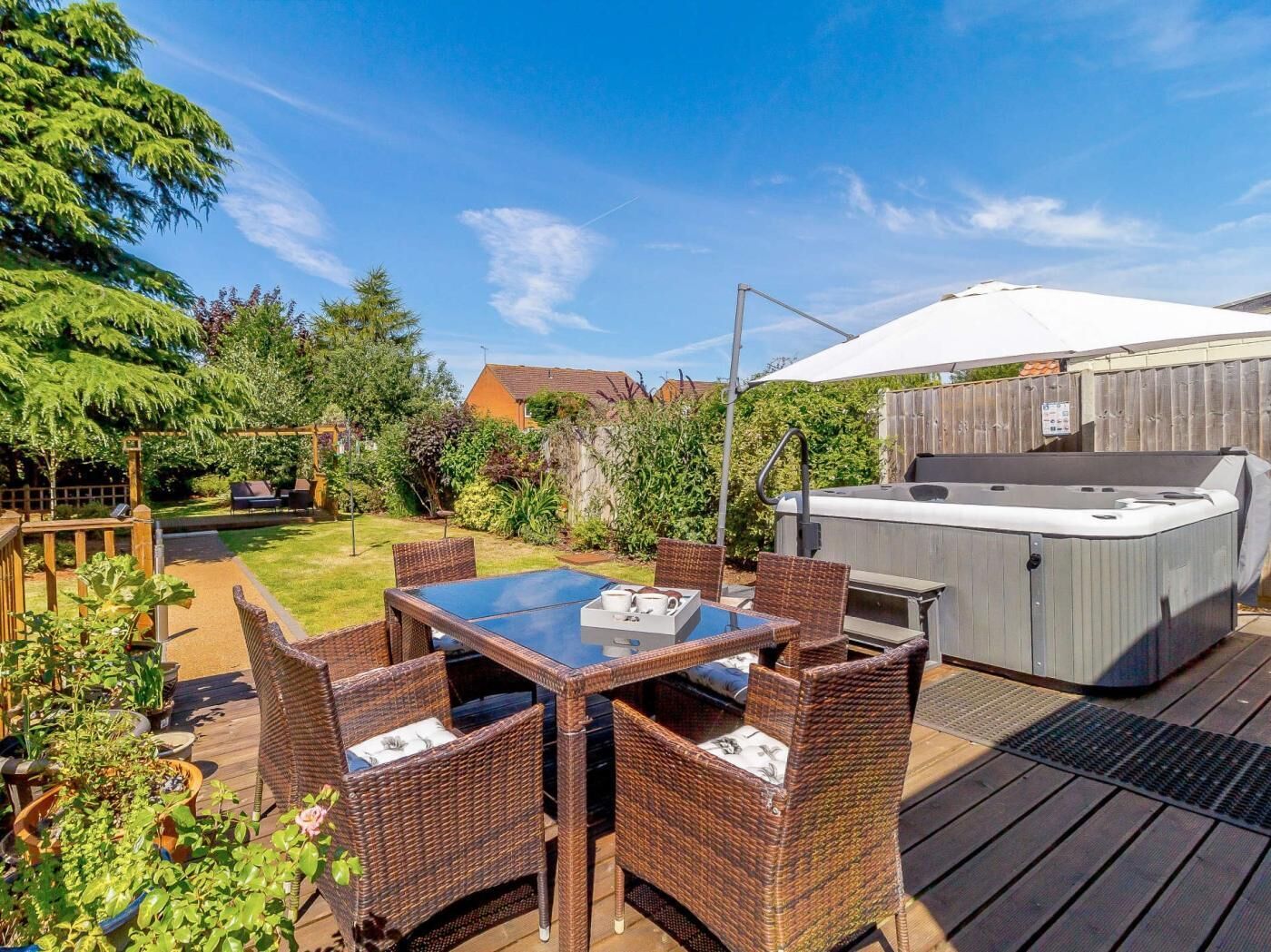 Eine Terrasse mit Whirlpool, Korbmöbeln und einer Holzterrasse.