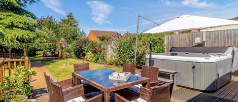 Eine Terrasse mit Whirlpool, Korbmöbeln und einer Holzterrasse.