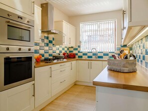A modern kitchen with white cabinetry, a built-in oven, a gas stove, and a window with blinds. - 3 Bed in King's Lynn (oc-43259) (Dersingham)