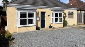 A two-story house with a dark roof, white-framed windows, and a blue door. - 3 Bed in King's Lynn (oc-43259) (Dersingham)