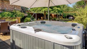 A hot tub with a canopy, surrounded by outdoor furniture and greenery. - 3 Bed in King's Lynn (oc-43259) (Dersingham)
