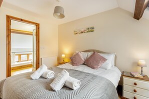 A bedroom with a bed, two bedside tables, a window, a mirror, and a painting on the wall. - 3 Bed in Whitchurch Canonicorum (oc-43398) (Whitchurch Canonicorum)