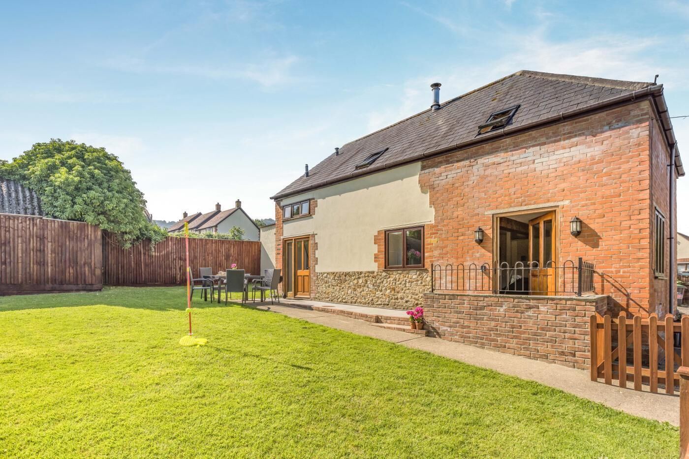A two-story house with a brick exterior, a wooden deck, and a well-maintained lawn.