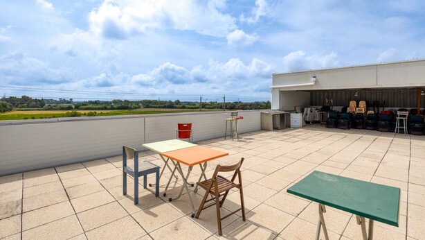 A rooftop terrace with a table, chairs, and a view of the landscape.