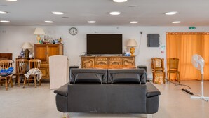 A room with a black sofa, wooden cabinet, and a television on the wall.