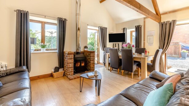 A cozy living room with a fireplace, leather sofas, a dining area, and a TV. - 3 Bed in Whitchurch Canonicorum (oc-43395) (Whitchurch Canonicorum)