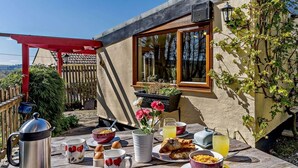 A breakfast setup with a coffee pot, mugs, plates, and food on an outdoor table. - 2 Bed in Lampeter (oc-43293) (Tregaron)