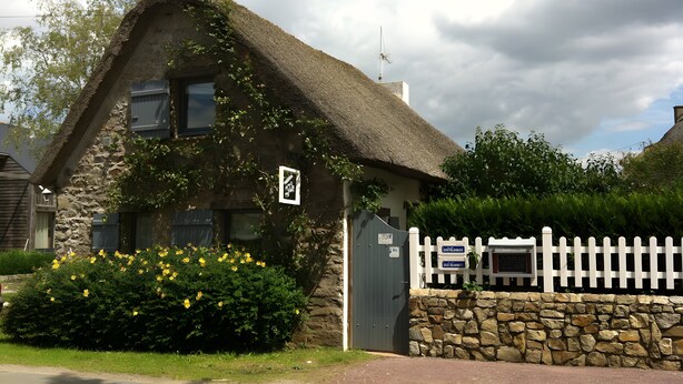 A stone cottage with a thatched roof, a white picket fence, and a bush with yellow flowers in front. - Gîte La Chaumière de Claire - Anouck (Saint-André-des-Eaux)