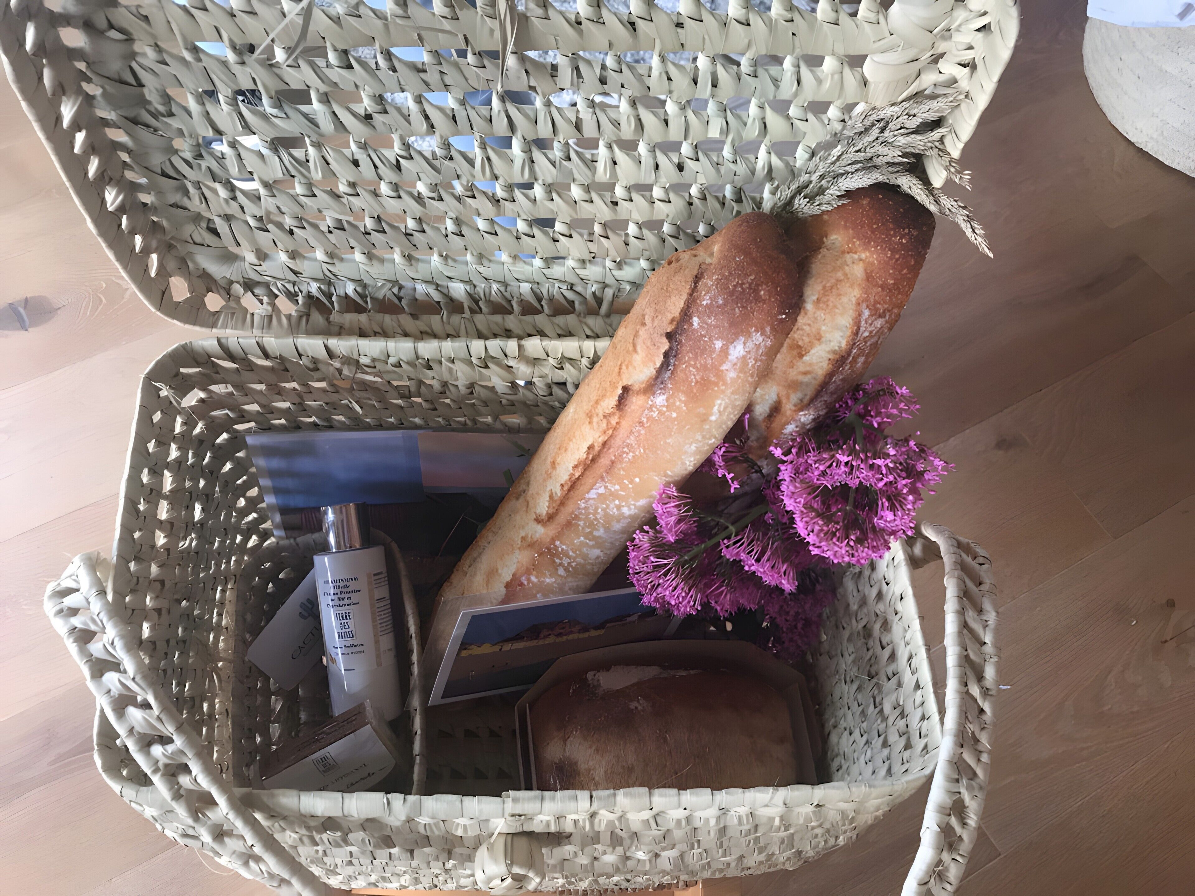 Uma cesta de vime com pão, uma garrafa e um cartão.