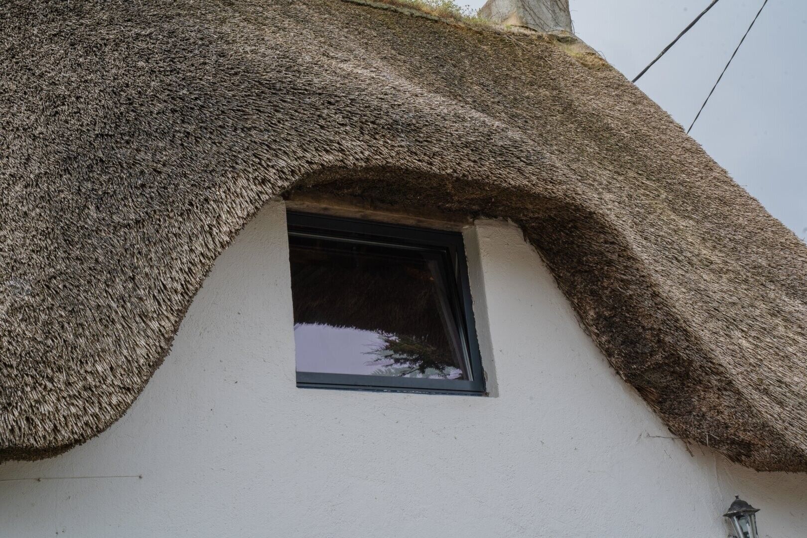 A thatched roof house with a small window.