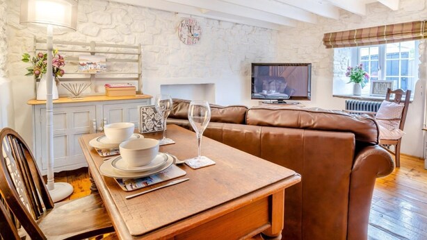 Ein gemütliches Wohnzimmer mit Esstisch, Ledersofa und Fernseher.