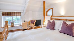Ein Schlafzimmer mit Bett, Stuhl, Fenster und Heizkörper.