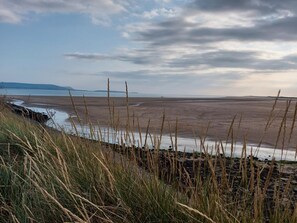 A coastal landscape with a beach, grassy dunes, and a distant shoreline. - 1 Bed in Kidwelly (oc-43409) (Kidwelly)
