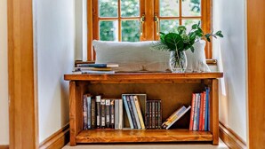 A wooden bookshelf with books, a cushion, and a plant. - 4 Bed in Hereford (oc-44213) (Hereford)