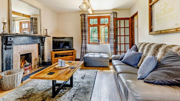 A living room with a fireplace, a television, a sofa, and a large window. - 4 Bed in Hereford (oc-44213) (Hereford)