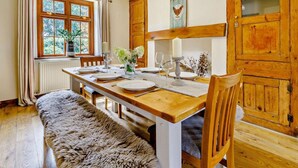 A dining room with a wooden table set for four, a bench, and a window with curtains. - 4 Bed in Hereford (oc-44213) (Hereford)