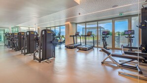 Un gimnasio moderno con diverso equipamiento de ejercicio, amplias ventanas y un diseño espacioso.