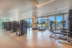 A modern gym with various exercise equipment, large windows, and a spacious layout. - Bayline Beach2 - Sea View Apartment in Armação (Armação de Pêra)