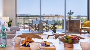 Un comedor con una mesa dispuesta para el desayuno, con cruasanes, un frutero y una botella de agua.