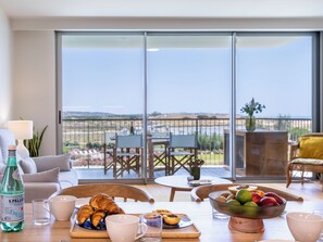 A dining area with a table set for breakfast, including croissants, a fruit bowl, and a bottle of water. - Bayline Beach2 - Sea View Apartment in Armação (Armação de Pêra)