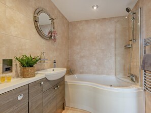 Ein modernes Badezimmer mit freistehender Badewanne, einem Waschtisch und einem Spiegel.