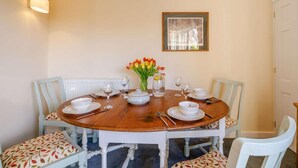 A dining table with white chairs, a vase of tulips, and a framed picture on the wall. - 2 Bed in Wrexham (oc-43916) (Overton)