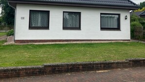 Une maison de plain-pied avec un toit à pignon, une petite lucarne et des fondations en briques.